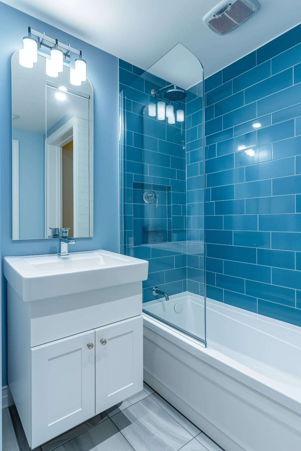 Bright bathroom with blue tiled walls white sink and clear glass shower enclosure