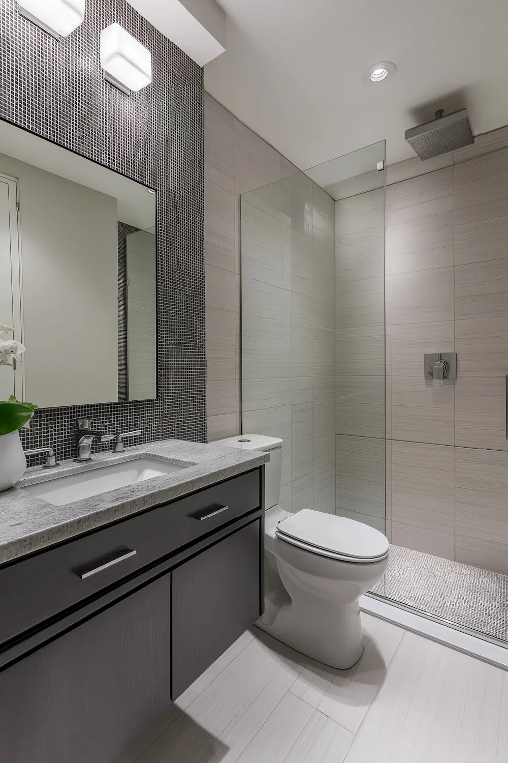 Modern bathroom with a shower glass door granite countertop and patterned black tile wall