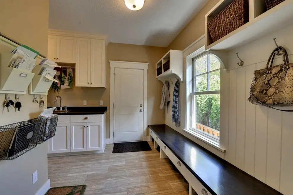 Bright mudroom with a bench shelves hooks and a sink near the door