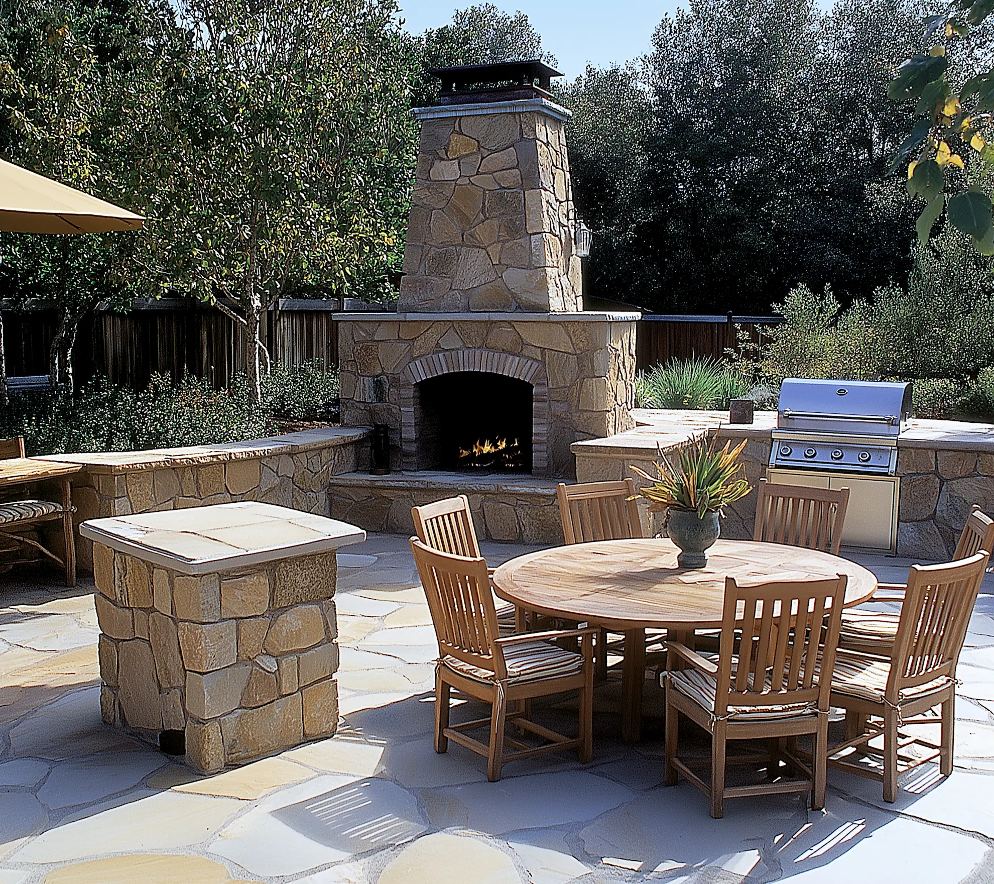 Cozy Patio Kitchen with a Fire Pit - stone fireplace stainless steel grill and wooden dining set